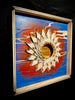 Colorado-Snow-mixed-media-wood-art-artist-Cie-Hoover-Decorative wall art with a sun-like design on a blue background, framed in wood