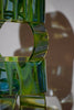 Lighthouse-glass-artist-Evan-Seeling-A sculptural glass vase made of stacked, wavy translucent green glass sections with a central cutout.