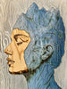 Mountains-of-the-Mind-Cold-Composure-closeup-mixed-media-wood-art-artist-Cie-Hoover-Artistic depiction of a face with gold and blue tones on a textured background